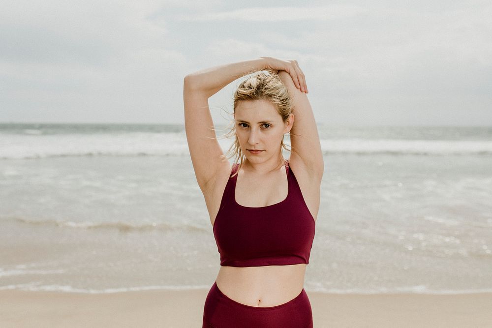 Young woman stretching by the beach