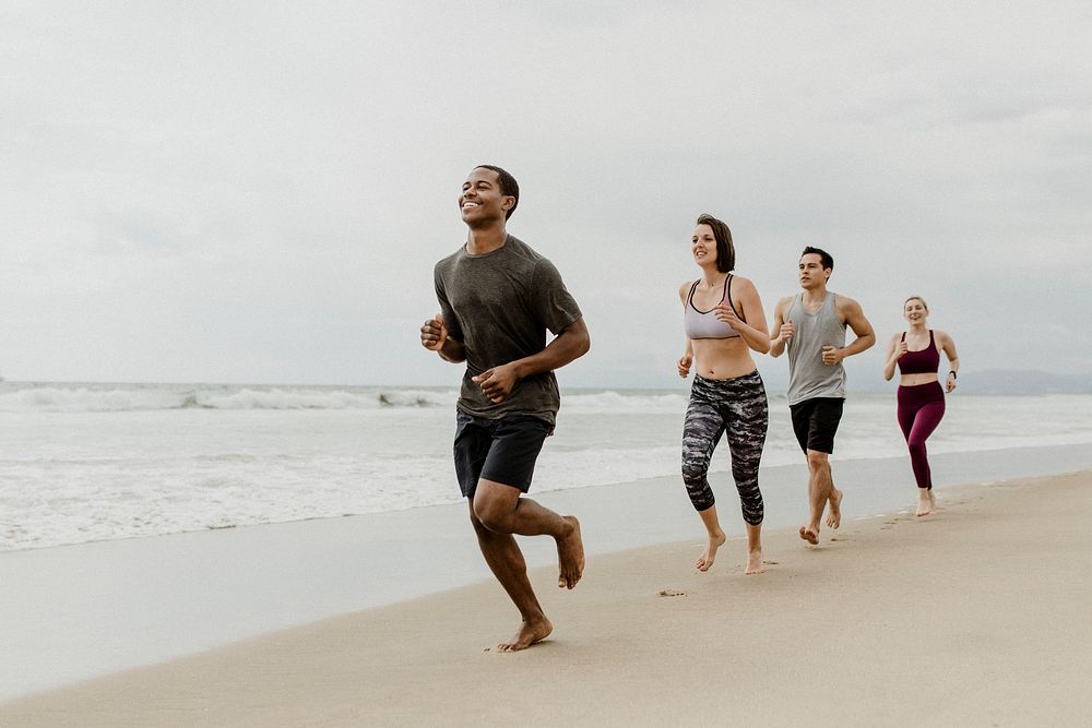 Happy friends jogging together at the beach