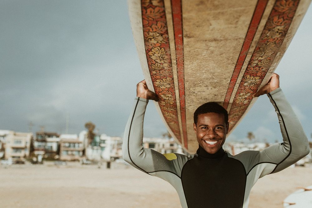 Cheerful man carrying a surfboard