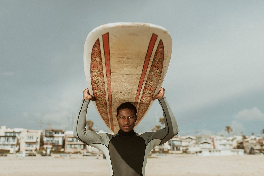 Surfer carrying a surfboard at the beach