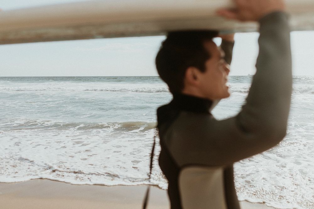 Surfer carrying a surfboard at the beach