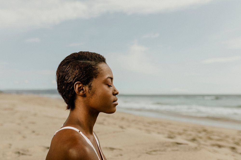 Black woman meditating on the beach