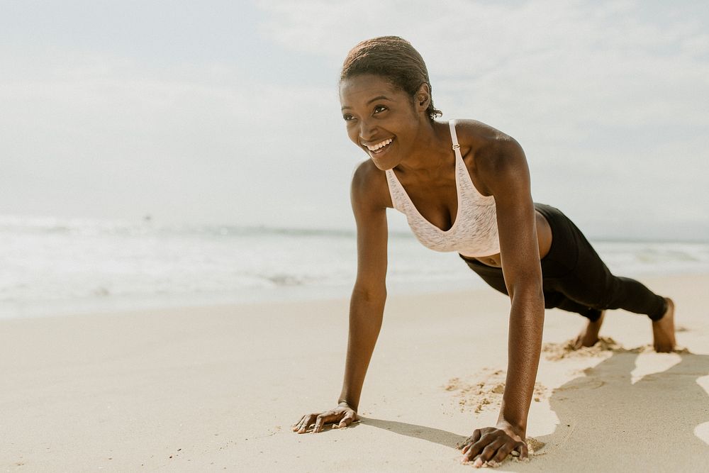 Happy woman doing pushups at the beach