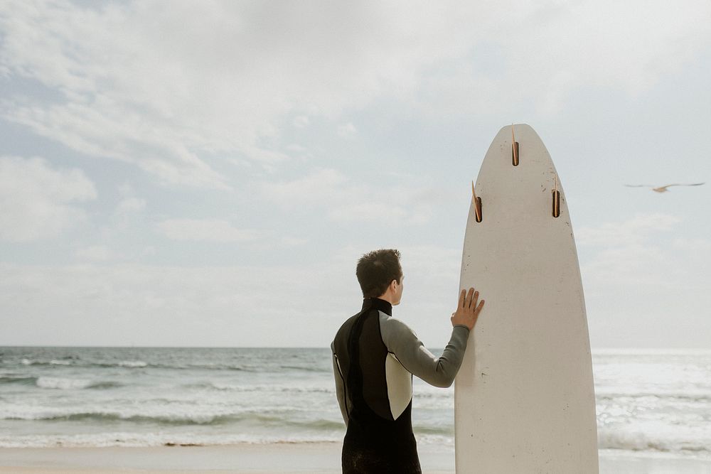 Man with a surfboard looking at the sea
