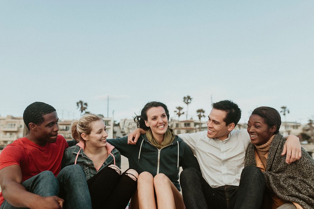 Cheerful friends hugging on the beach