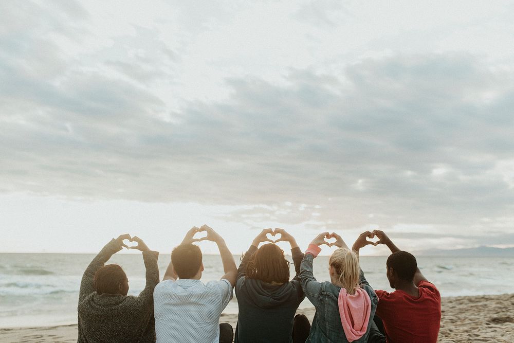 Friends making love heart hands at the beach