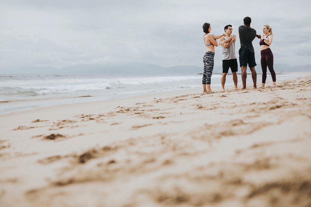 Diverse friends stretching at the beach