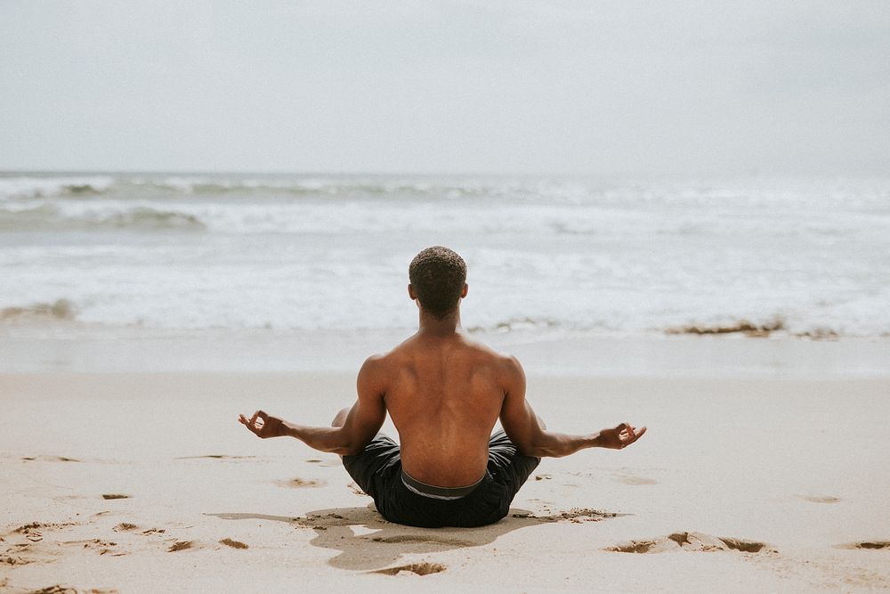 Black man meditating at the beach