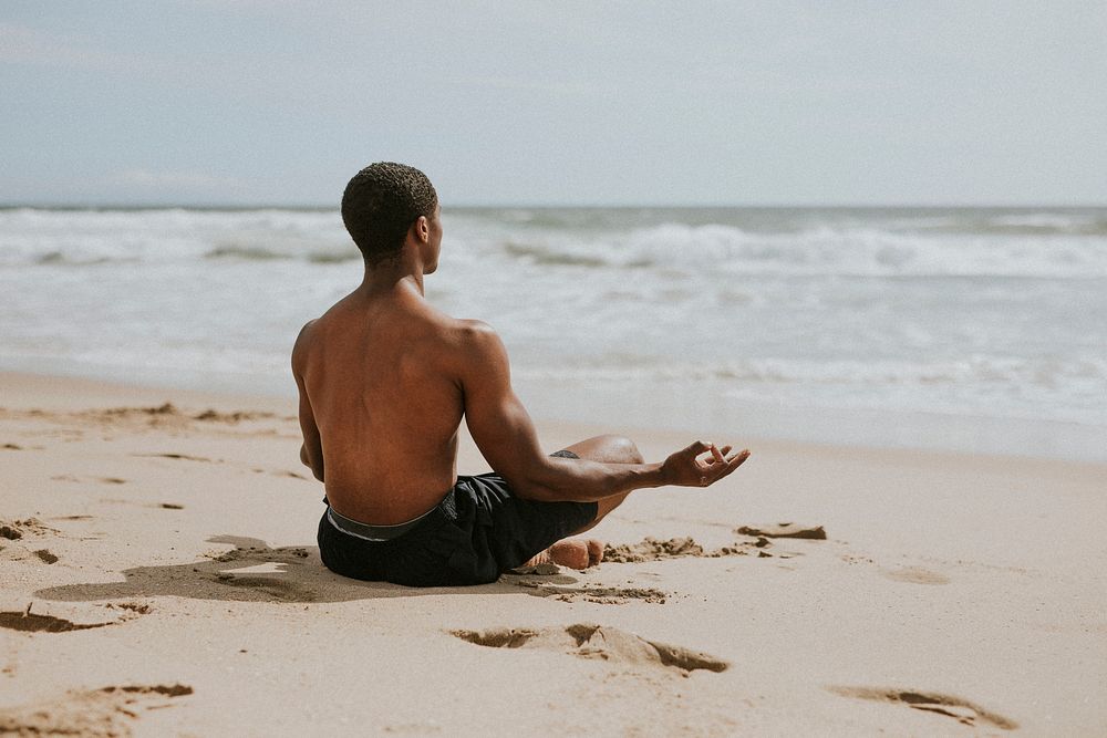 Black man meditating at the beach