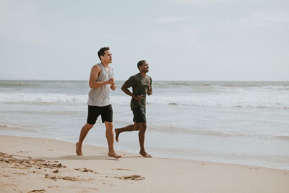 Happy friends jogging at the beach together