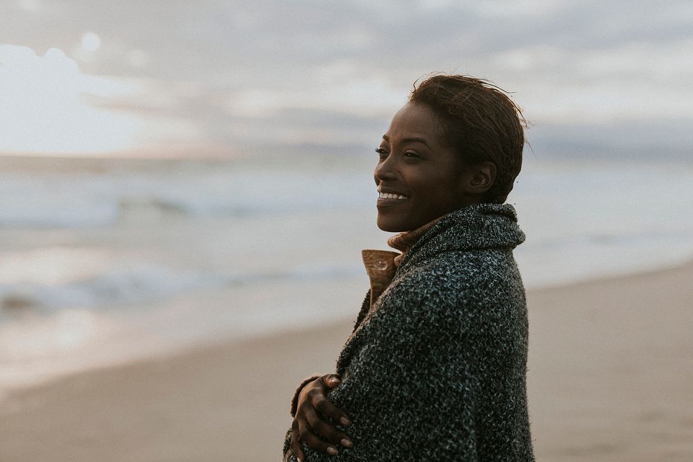 Cheerful black woman on the beach at sunset