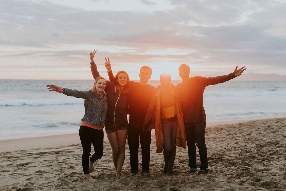 Happy friends enjoying the beach at sunset