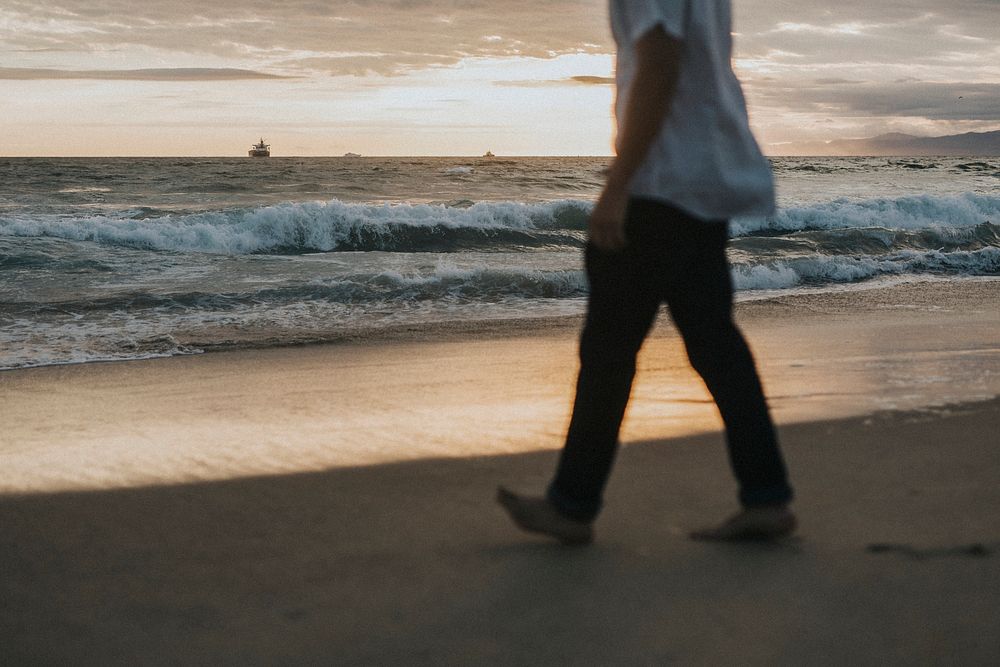 Man walking on the beach at sunset