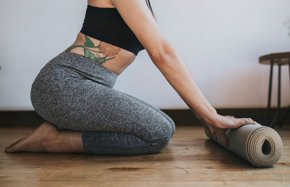 Sporty woman rolling a yoga mat