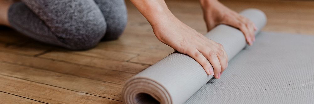 Sporty woman rolling a yoga mat