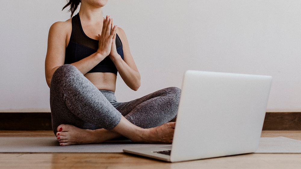 Sporty woman learning a yoga online via a laptop