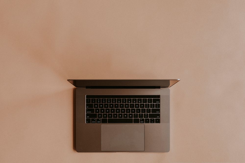 Laptop lying on a peach background