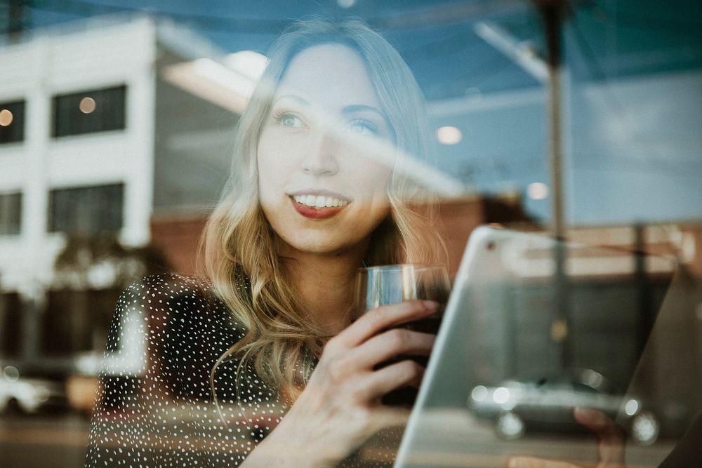 Woman with a drink using a digital tablet