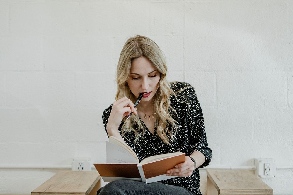 Woman thinking while writing on her notebook