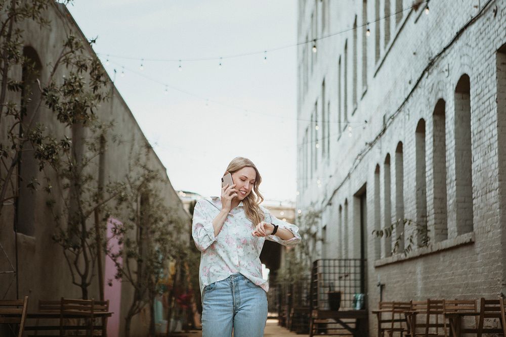 Woman on the phone walking down the street looking at the time