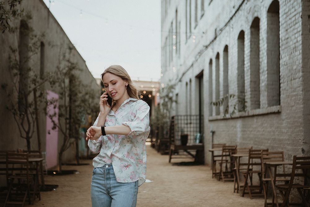 Woman on the phone walking down the street looking at the time