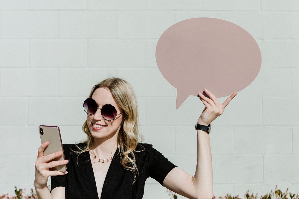 Woman showing a blank speech bubble while using her phone