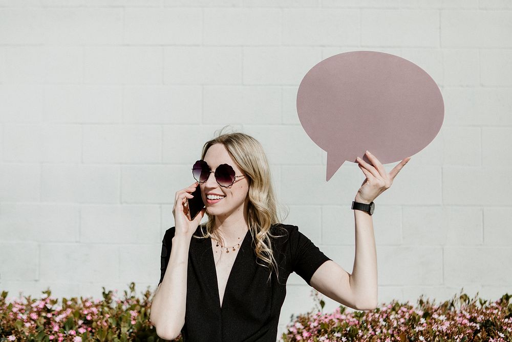 Woman showing a blank speech bubble while using her phone