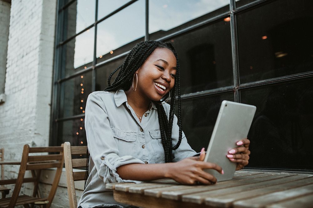 Black happy woman using a digital tablet outdoors