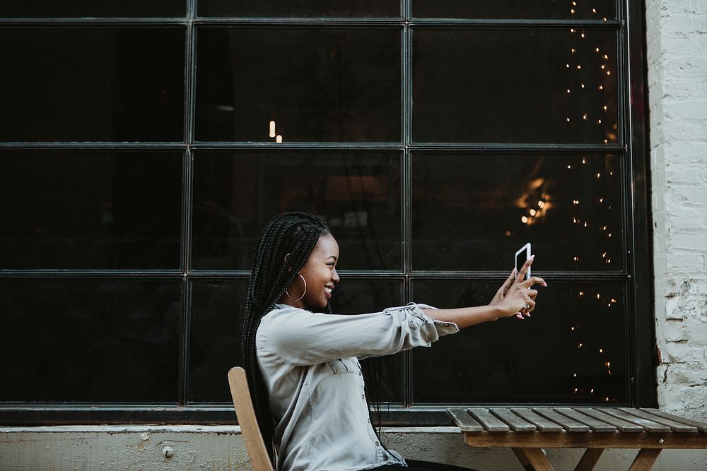 Cheerful black woman taking a selfie at an outdoor cafe