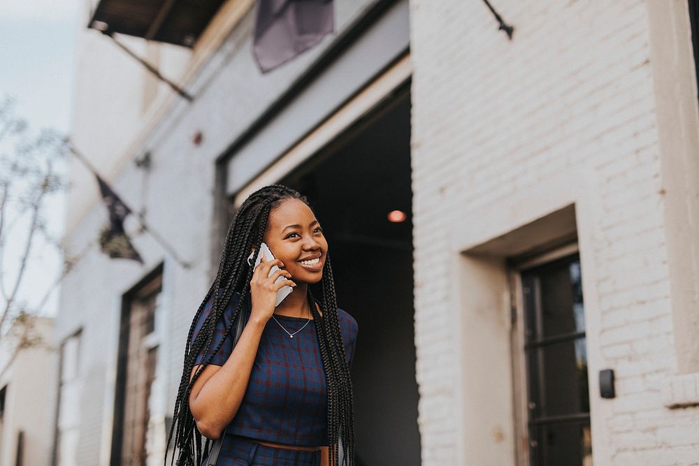 Happy black woman talking on the phone while walking on the streets