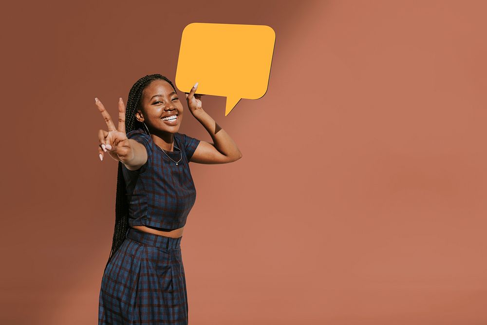 Cheerful black woman showing a v sign with a blank speech bubble