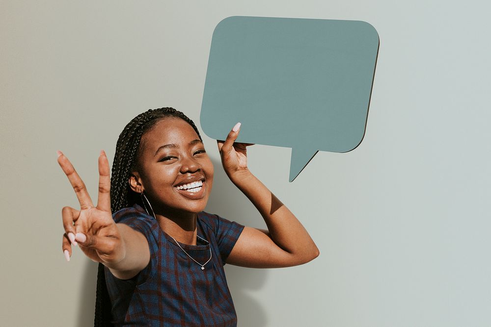 Cheerful black woman showing a v sign with a blank speech bubble