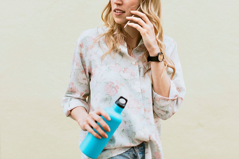 Woman on the phone carrying a thermal bottle