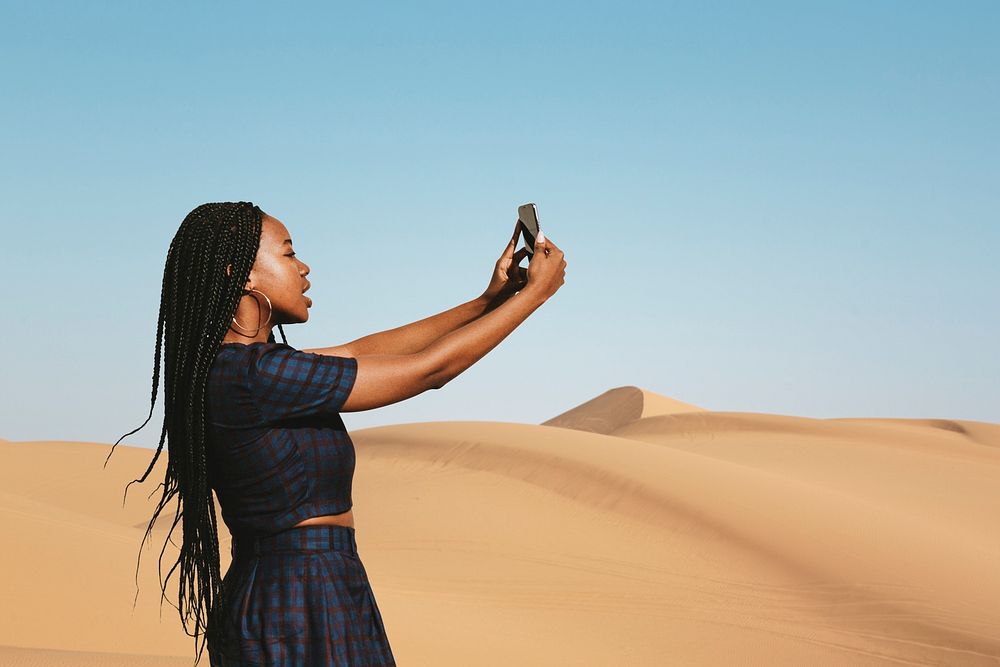 Black woman taking a photo on a desert