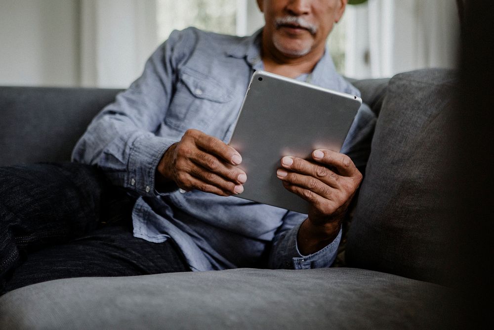 Elderly man using a tablet on a couch