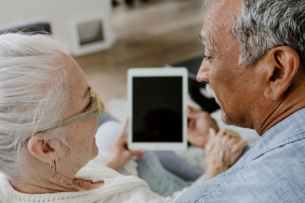 Elderly couple using a tablet on a couch