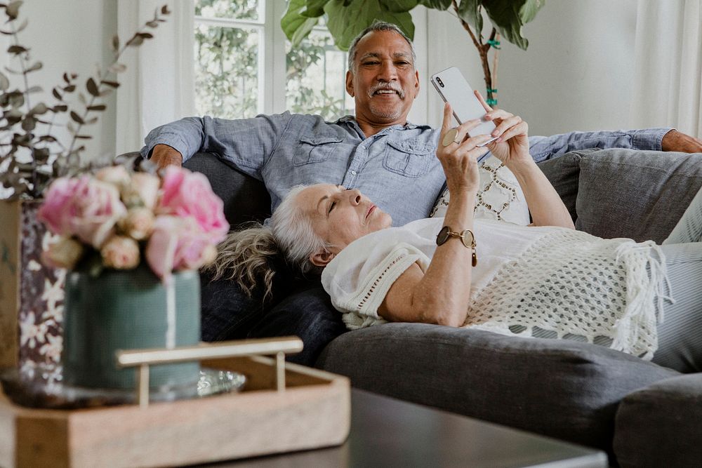 Elderly couple using a phone on a couch