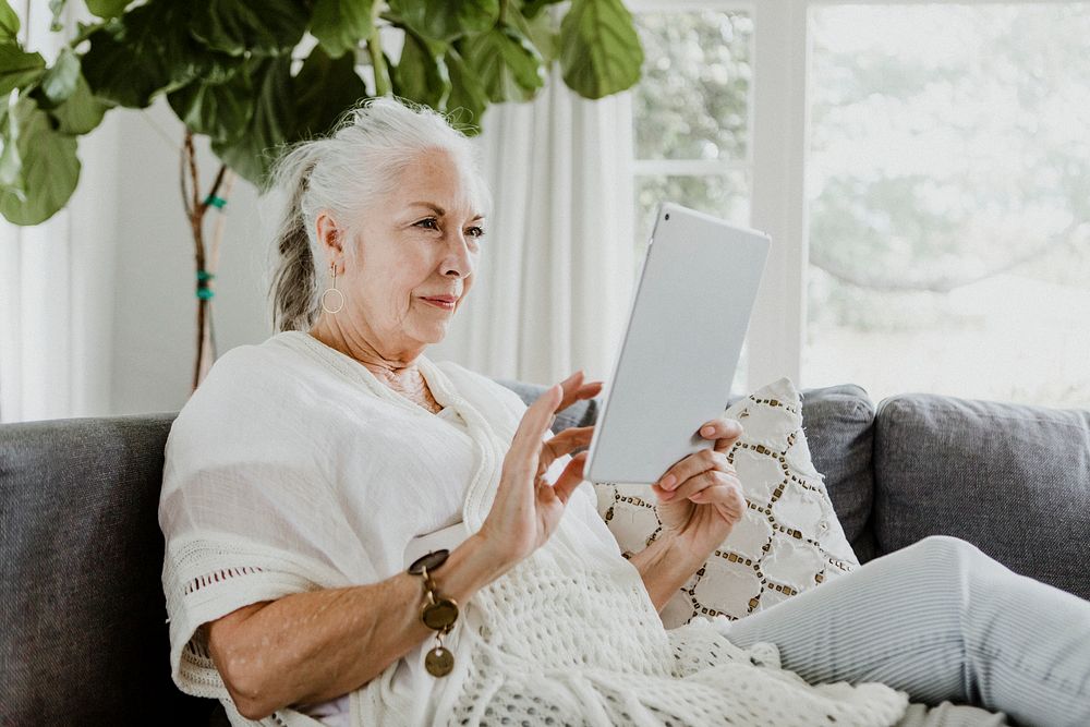 Elderly woman using a tablet on a couch