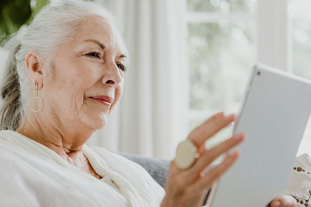 Elderly woman using a tablet on a couch