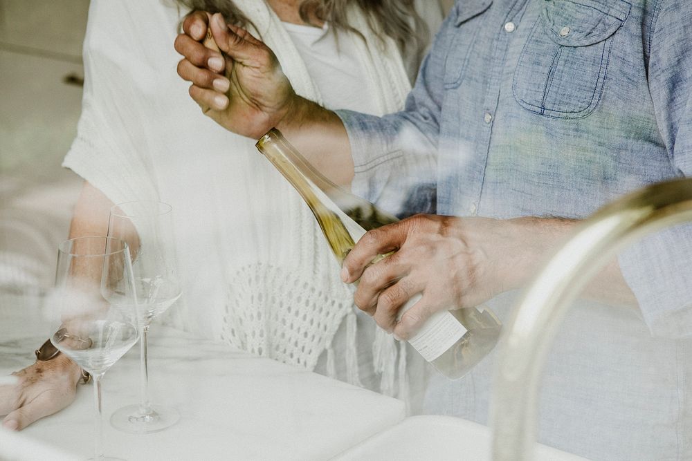 Elderly man opening a white wine bottle