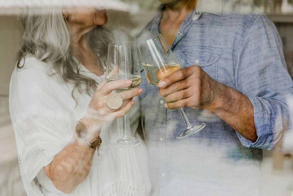 Elderly couple clinking their white wine glass