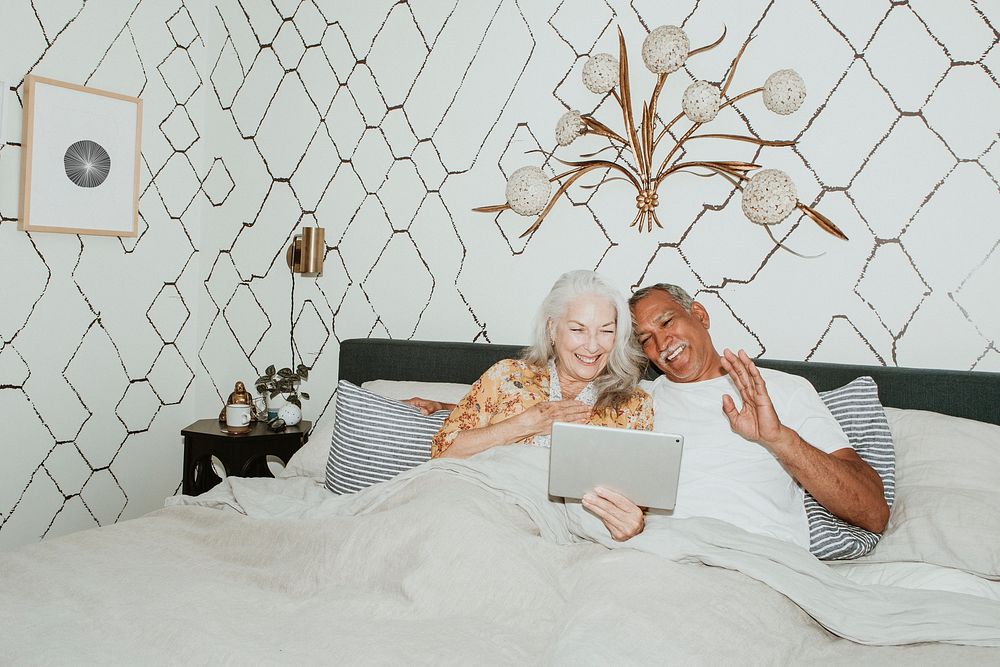 Elderly couple having a video call in bed