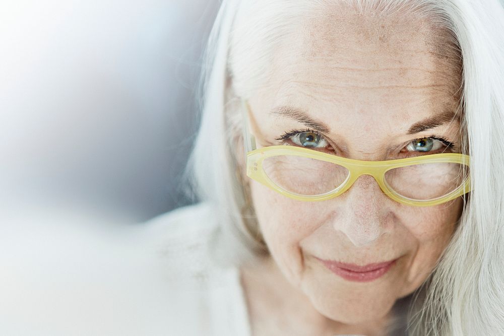 Portrait of an elderly woman with a yellow eyeglasses