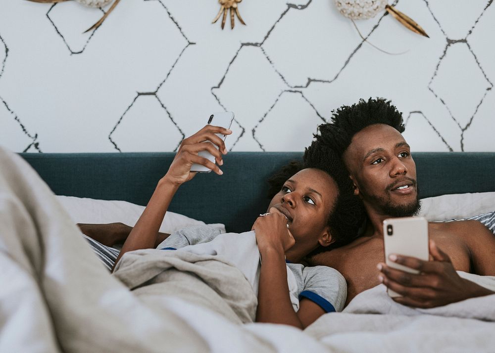 Black couple in bed using a smartphone