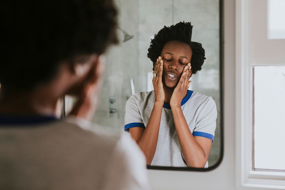 African woman standing by the mirror in the bathroom