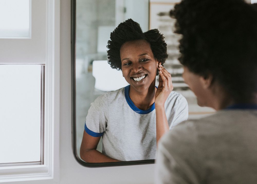 African woman standing by the mirror in the bathroom