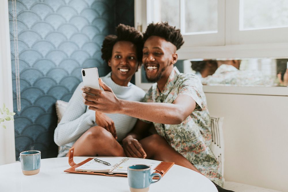Happy black couple taking a selfie at home with a mobile