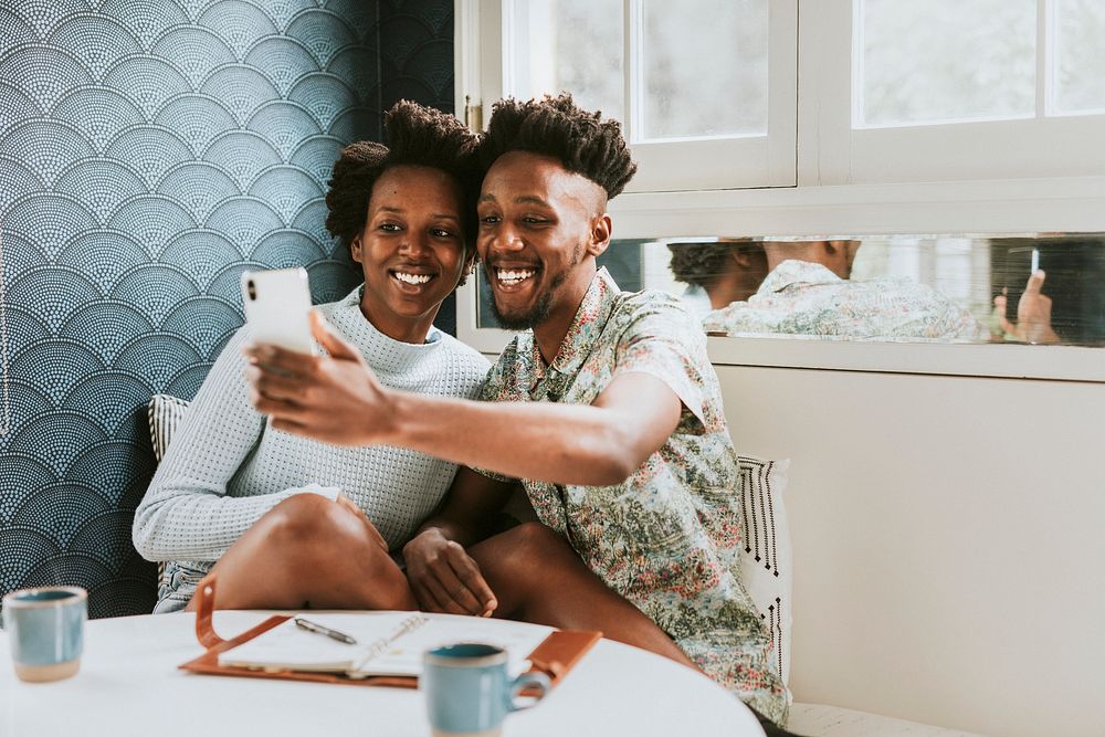 Happy black couple taking a selfie at home with a mobile