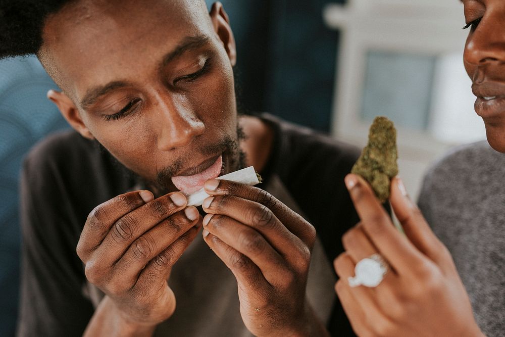A man licking up a weed joint