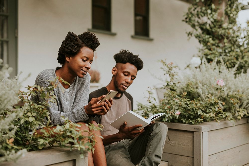 Black couple reading a book and playing on the phone